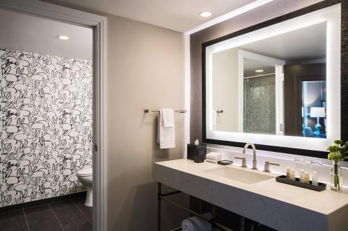 a bathroom with a sink and a mirror and a toilet at The Lindy Renaissance Charleston Hotel in Charleston