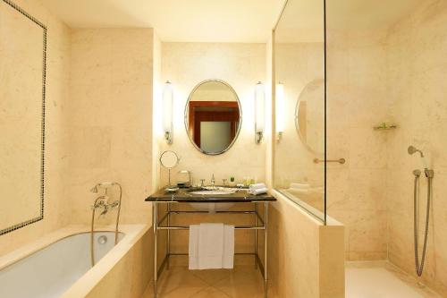 een badkamer met een wastafel, een bad en een spiegel bij The Westin Valencia in Valencia