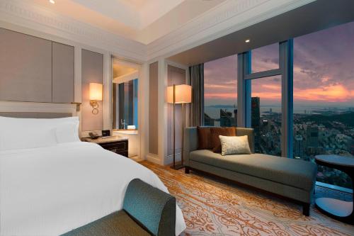 a bedroom with a bed and a couch and a window at The Westin Qingdao - Instagrammable in Qingdao