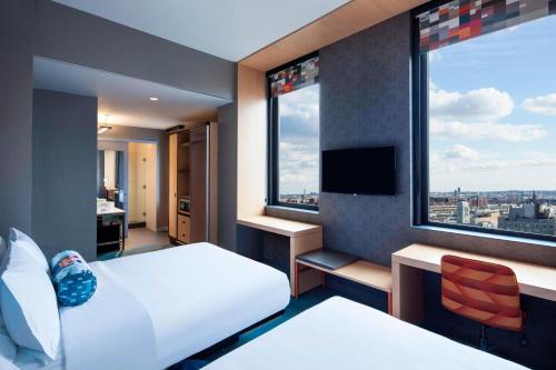 a hotel room with two beds and two windows at Aloft Long Island City-Manhattan View in Queens