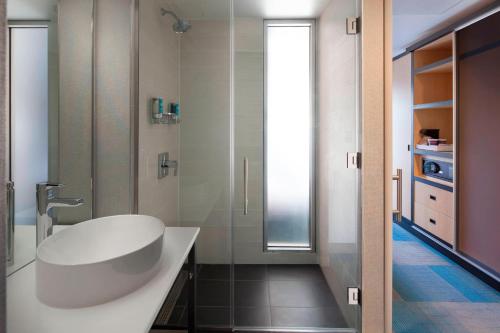 a bathroom with a white sink and a shower at Aloft Long Island City-Manhattan View in Queens