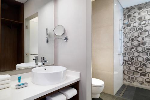 a bathroom with a sink and a toilet and a mirror at Aloft Me'aisam, Dubai in Dubai