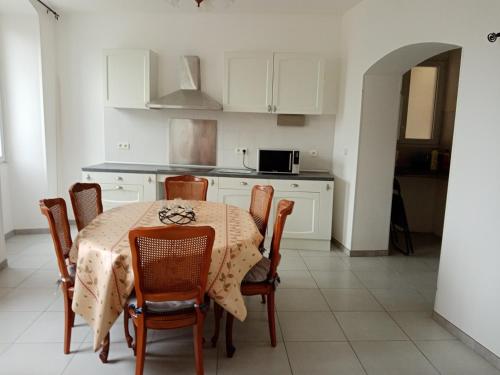 a kitchen with a table and chairs and a kitchen with white cabinets at Le passage de Gardie 