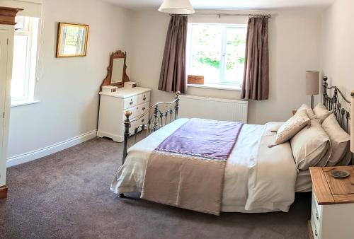 um quarto com uma cama, uma cómoda e um espelho em Oakcroft em Sidmouth