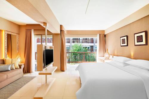 een slaapkamer met een groot wit bed en een bank bij Four Points by Sheraton Bali, Kuta in Kuta