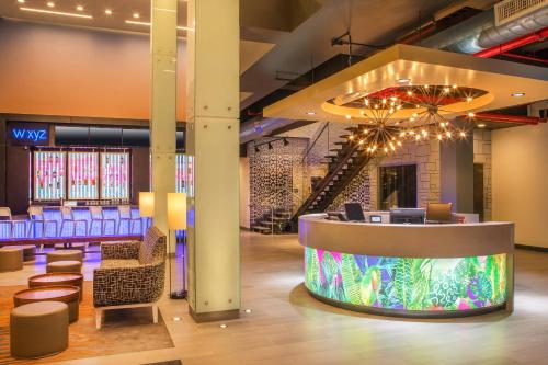 a lobby with a waiting area with chairs and a chandelier at Aloft New York LaGuardia Airport in Queens