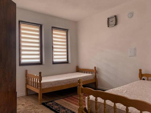 a bedroom with two beds and two windows at Dardania Apartments in Peje