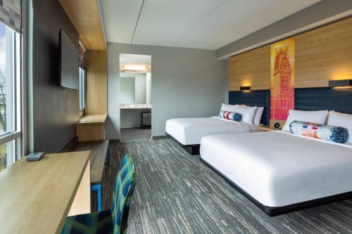 a hotel room with two beds and a desk at Aloft Louisville East in Louisville