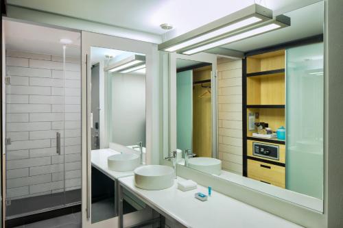 a bathroom with two sinks and a large mirror at Aloft Louisville East in Louisville