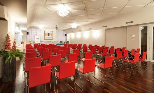 a large room with red chairs and tables and a room with at Hotel Lombardia in Milan