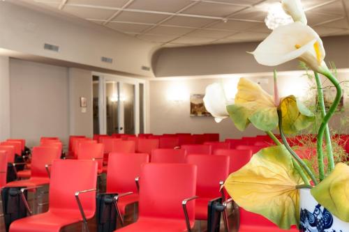 a room with red chairs and a vase with flowers at Hotel Lombardia in Milan