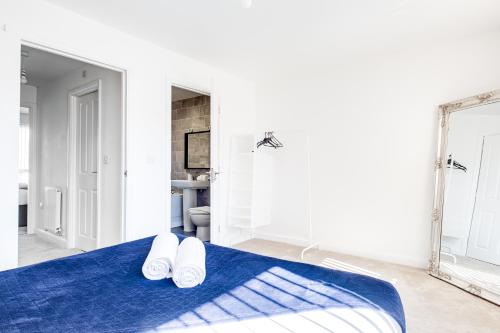 ein weißes Zimmer mit einem blauen Bett und einem Spiegel in der Unterkunft City Centre 3 Bedroom House - Family & Business in Birmingham