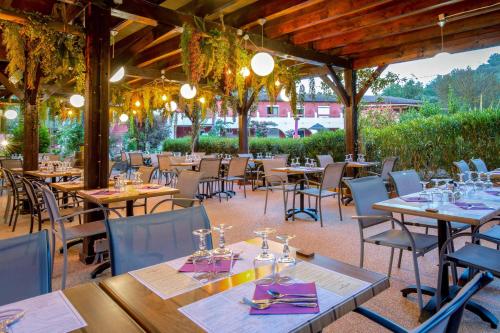a restaurant with wooden tables and chairs and a patio at Les Pins Blancs en Provence in Le Muy