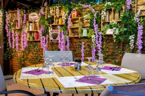 a table with wine glasses and purple flowers on a wall at Les Pins Blancs en Provence in Le Muy