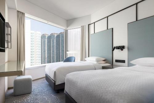 a hotel room with two beds and a large window at Four Points by Sheraton Hong Kong, Tung Chung in Hong Kong