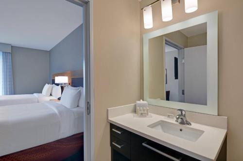 uma casa de banho com um lavatório, uma cama e um espelho. em TownePlace Suites by Marriott Indianapolis Downtown em Indianápolis