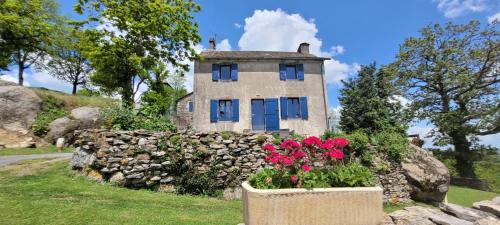 ein Steinhaus mit blauen Fenstern und Blumen davor in der Unterkunft Gîte à la tour de Peyrebrune in Alrance
