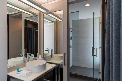 a bathroom with two sinks and a shower at Aloft College Station in College Station