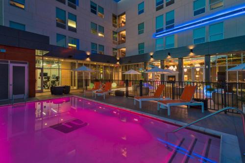 a pool at a hotel with chairs and a building at Aloft College Station in College Station
