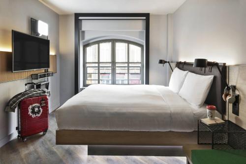 une chambre avec un grand lit et une fenêtre dans l'établissement Moxy Lille City, à Lille