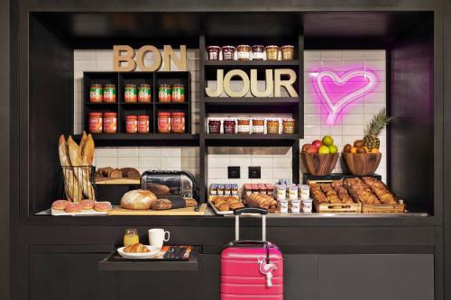 a bakery with a counter with pastries and a pink suitcase at Moxy Lille City in Lille