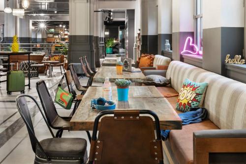 a restaurant with tables and chairs and a couch at Moxy Lille City in Lille