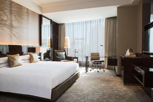 una camera d'albergo con un grande letto e una scrivania di Renaissance Shanghai Pudong Hotel a Shanghai