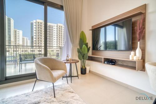 a living room with a tv and a chair at Sleek Studio at UNA Town Square Dubailand by Deluxe Holiday Homes in Dubai