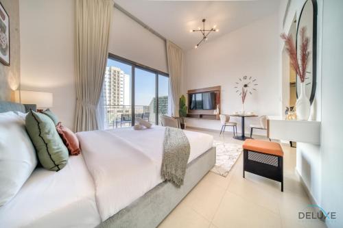 a bedroom with a white bed and a large window at Sleek Studio at UNA Town Square Dubailand by Deluxe Holiday Homes in Dubai