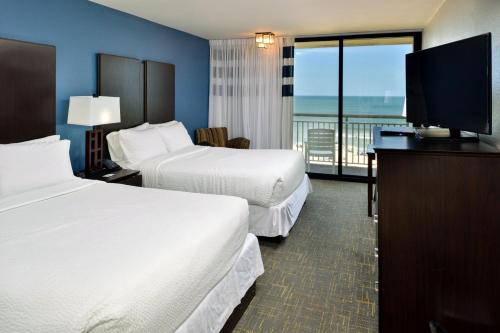 a hotel room with two beds and a flat screen tv at Four Points by Sheraton Virginia Beach Oceanfront in Virginia Beach