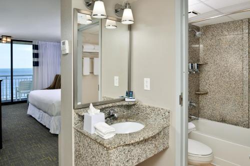 a bathroom with a sink and a tub and a toilet at Four Points by Sheraton Virginia Beach Oceanfront in Virginia Beach