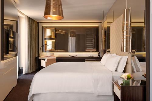 a bedroom with a large white bed and a bathroom at Excelsior Hotel Gallia, a Luxury Collection Hotel, Milan in Milan