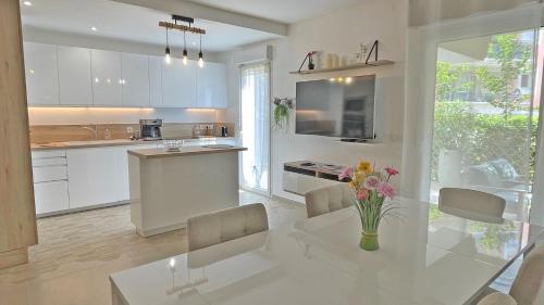 - une cuisine blanche avec une table, des chaises et un comptoir dans l'établissement Casa del Mar, à Sainte-Maxime
