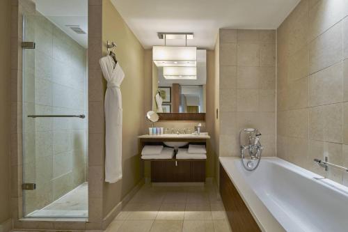 a bathroom with a tub and a shower and a sink at Threadneedles, Autograph Collection in London