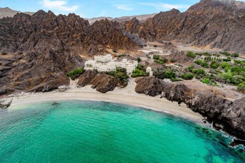 an aerial view of a resort on a rocky beach at Al Bustan Palace, a Ritz-Carlton Hotel in Muscat