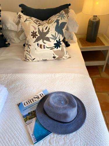 a hat sitting on top of a bed with a magazine at Pretty Historical Village House in Grimaud