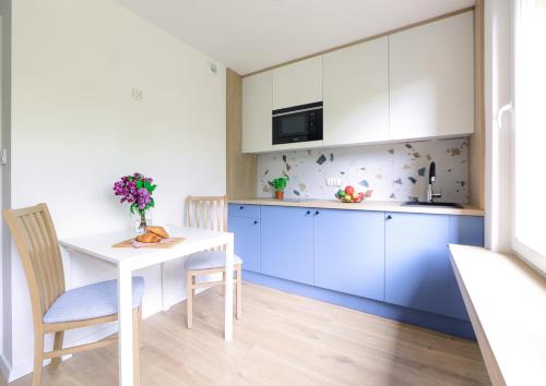 a kitchen with blue cabinets and a white table and chairs at Telimeny 31 in Krakow