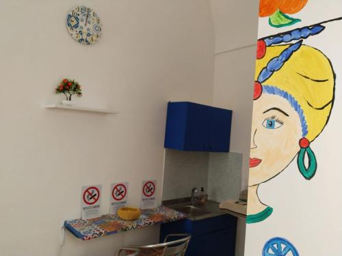 a kitchen with a painting of a woman on the wall at B&B Sikelia in Terrasini