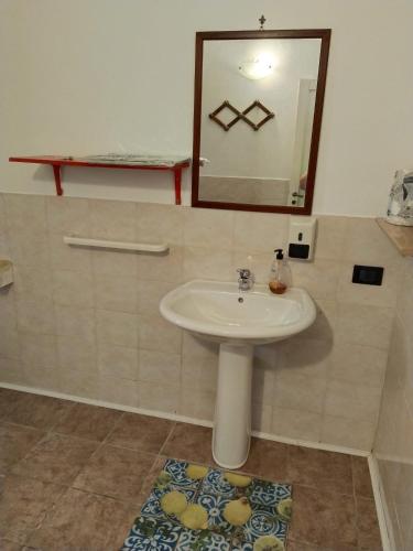 a bathroom with a sink and a mirror and a rug at B&B Sikelia in Terrasini