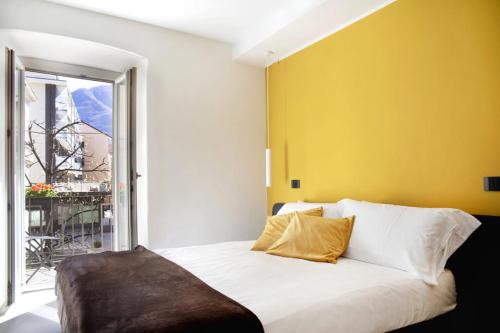 um quarto com uma cama branca e uma parede amarela em Ca Bussun em Domodossola