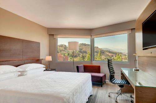 サンティアゴにあるシェラトン サンティアゴ ホテル ＆ コンベンション センターのベッドと大きな窓が備わるホテルルームです。