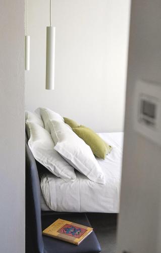 a bed with white pillows and a book on a chair at Ca Bussun in Domodossola