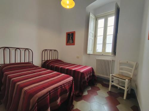 a bedroom with two beds and a chair and a window at Dimora del Sole in Martina Franca