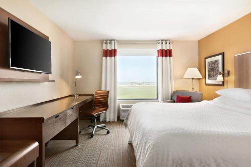 Habitación de hotel con cama, escritorio y TV. en Four Points by Sheraton Fargo Medical Center, en Fargo