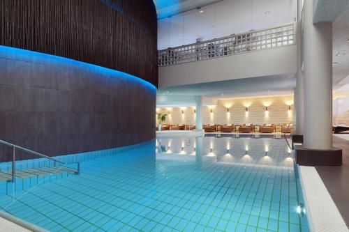 uma grande piscina com piso de azulejo azul em Le Méridien Stuttgart em Stuttgart