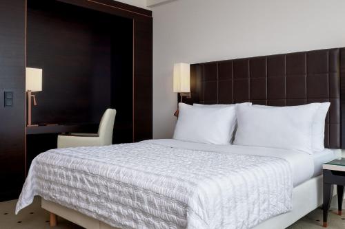 a bedroom with a large bed with a white comforter at Le Méridien Stuttgart in Stuttgart