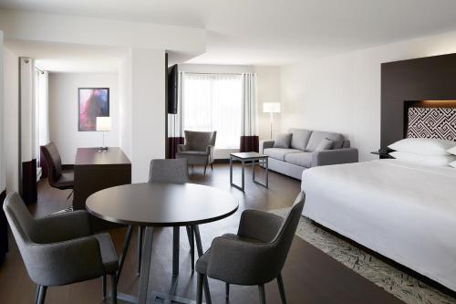 Habitación de hotel con cama, mesa y sillas en Four Points by Sheraton Lévis Convention Centre, en Lévis