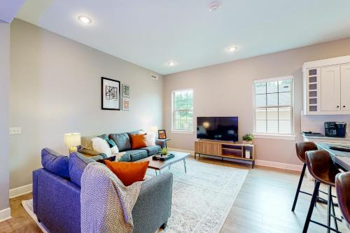 a living room with a blue couch and a tv at Bentonvilla in Bentonville