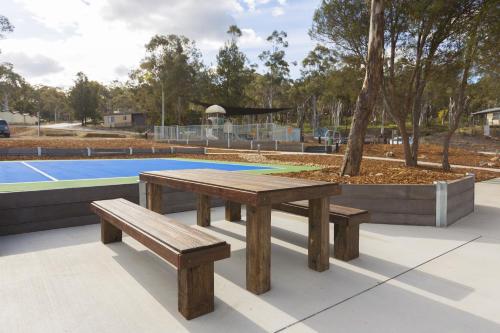 a picnic table and bench next to a pool at Alivio Tourist Park Canberra in Canberra