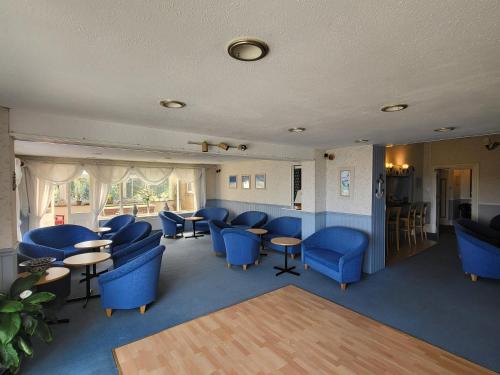 a waiting room with blue chairs and tables at Eastmount Hall Hotel in Shanklin